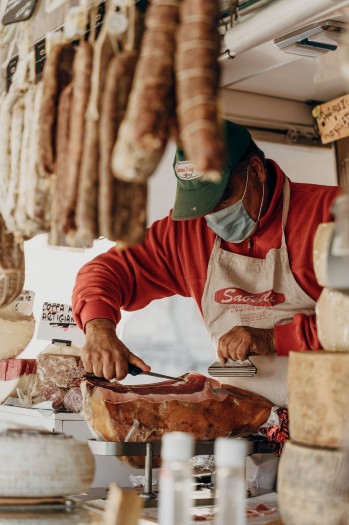 Ein Lebensmittelhändler in Italien schneidet eine Scheibe von einem großen Prosciutto-Block ab