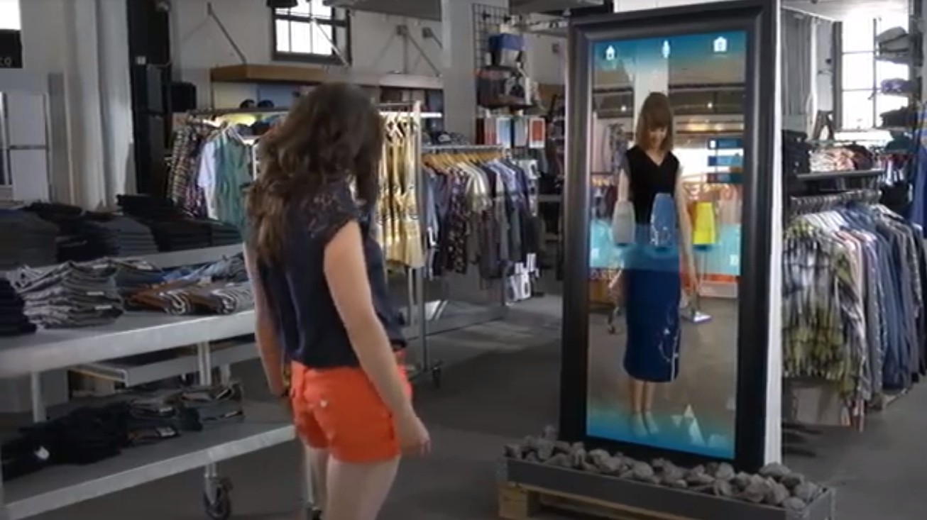 Eine Frau, die Kleidung virtuell anprobiert. Source: The Future of Augmented Reality: 10 Awesome Use Cases, https://www.youtube.com/watch?v=WxzcD04rwc8
